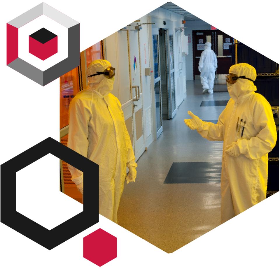 two scientist in clean room PPE talking to each other in a hall
